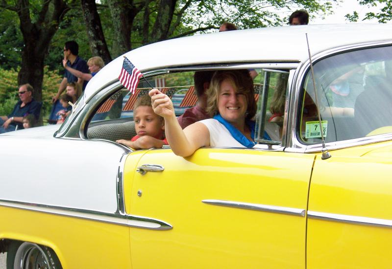 Pam Nowick of Marion waves to the crowd. Inside the car was Zola Campbell, who at four weeks old participated in her first Fourth of July parade. BY MATTHEW BERNAT